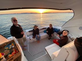A cheerful group enjoys cocktails on a boat during a stunning sunset, creating the perfect atmosphere for relaxation and celebration on the water.