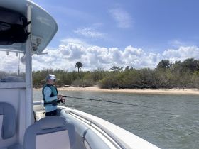 A child enjoys a fishing experience from a boat, surrounded by lush greenery and a serene waterway — a perfect day for family outdoor adventures.