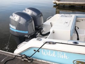 Close-up view of the outboard motors on a boat named 'Wild Fish', showcasing the sleek design and functionality of Yamaha engines.