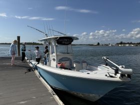 A group of people, including children, gather around a fishing boat at the dock, preparing for a day of fishing adventures on the water.