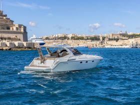 A sleek yacht navigates the vibrant waters near historic architecture, showcasing the beauty of maritime exploration.