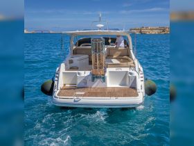 A stunning view of a yacht from the back, showcasing its elegant design and inviting seating area, perfect for relaxing on the water.