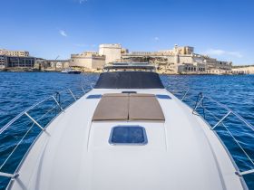 A stunning view from the front of a yacht cruising in clear waters, showcasing a historic fortress in the background — perfect for scenic boat tours.