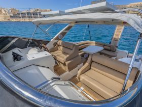 A spacious interior view of a luxury boat's helm and seating area, showcasing comfortable furnishings and a stylish design, perfect for relaxing on the water.