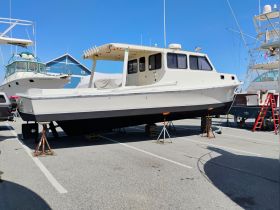 A powerboat is showcased in a marina, elevated on stands for maintenance, surrounded by other vessels — ideal for boat enthusiasts and potential buyers.