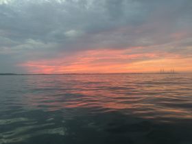 A stunning sunset casts vibrant colors over the water, creating a picturesque scene perfect for evening boat trips or romantic getaways.
