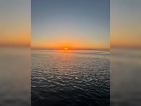 A serene sunset over calm waters, creating a picturesque backdrop for evening boat outings or romantic cruises.