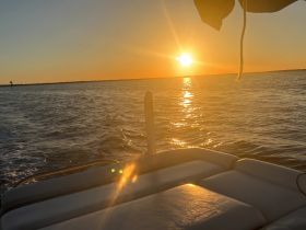 A serene sunset view from the deck of a boat, showcasing the tranquil waters and golden hues of the evening sky — perfect for romantic cruises or peaceful getaways.