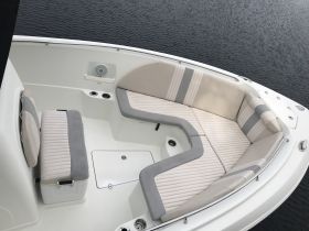 A clean and spacious interior view of a boat's seating area, featuring comfortable cushions and a cooler, perfect for relaxing on the water.