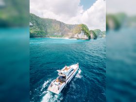 An aerial view of a boat cruising through vibrant turquoise waters, surrounded by stunning cliffs and lush greenery — a perfect scene for exploring beautiful island destinations.