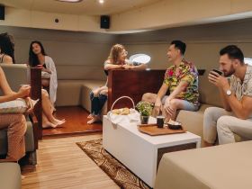 A lively gathering in the cabin of a boat, featuring friends enjoying snacks and drinks in a cozy lounge setting.