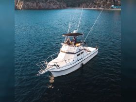 A fishing boat with guests enjoying the ocean view, showcasing a perfect day on the water.