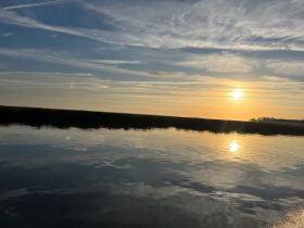 A serene sunset over calm waters, reflecting the vibrant colors of the sky — a perfect backdrop for peaceful boating experiences.