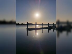 A serene view of a dock at sunset, with reflections on the water, creating a tranquil atmosphere.