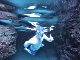 A snorkeler gives a thumbs up while exploring underwater, showcasing the excitement of marine adventures.