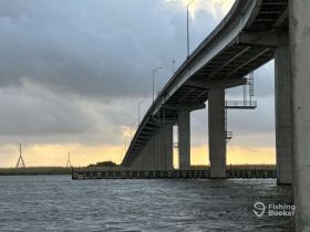 A scenic view of a bridge over water during sunset, capturing the tranquil atmosphere of the surroundings.