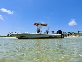 A sleek speedboat anchored in shallow waters, showcasing its design against a clear blue sky — perfect for day trips and water adventures.