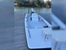 A fishing boat docked at the pier, showcasing its spacious deck and equipment, perfect for a day on the water.