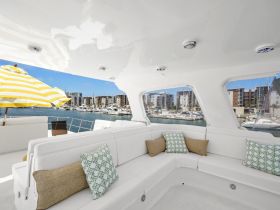 A stylish interior view of a boat's lounge area featuring comfortable seating and a vibrant yellow umbrella, perfect for relaxing while enjoying the marina views.