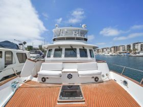 A spacious interior view of a boat's helm area, featuring comfortable seating and a polished wooden deck, perfect for relaxing while cruising.
