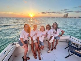 A group of friends poses for a photo on a boat at sunset, celebrating their time together on the water — perfect for memorable outings and gatherings.