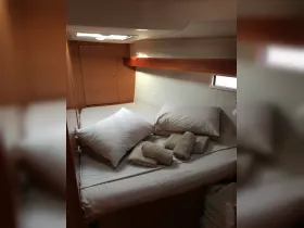 Cozy cabin interior featuring a neatly made bed with pillows and towels, perfect for relaxing on a boat getaway.