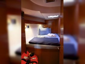 Cozy cabin interior featuring a comfortable sleeping area with neatly arranged linens, perfect for relaxing on a sailing adventure.