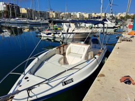 A sleek speedboat docked at a marina, showcasing its clean lines and inviting seating area, perfect for a day on the water.