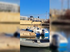 A sleek speedboat docked at a marina, showcasing its vibrant design against a backdrop of urban architecture.