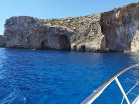 A stunning view of rocky cliffs along a vibrant blue coastline, showcasing the natural beauty of the area — perfect for scenic boat tours.