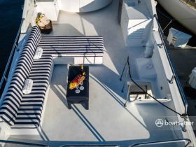 A stylish interior view of a boat's lounge area featuring striped seating and a table set with champagne and snacks, perfect for relaxing on the water.