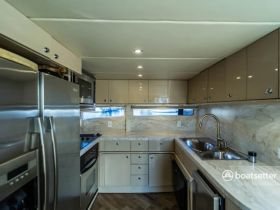 A modern and spacious kitchen area inside a boat, featuring stainless steel appliances and ample storage, perfect for preparing meals while on the water.