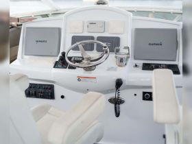 A detailed view of the helm and console area inside a boat, showcasing the steering wheel and electronic displays, perfect for navigation and control.