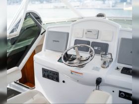 A detailed view of the helm and console area inside a boat, showcasing the steering wheel and navigation equipment, perfect for understanding the boat's operational features.