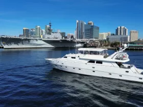 A stunning aerial view of a luxurious yacht cruising near a historic naval ship and the skyline of a bustling city, showcasing the perfect blend of maritime elegance and urban scenery.