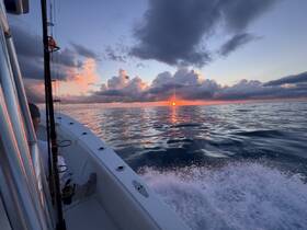 A serene sunset view from a fishing boat, capturing the tranquil waters and vibrant colors of the sky — perfect for evening fishing trips.