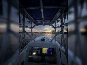 A view from the helm of a boat at sunset, showcasing the console and navigation equipment — perfect for those who love boating adventures.