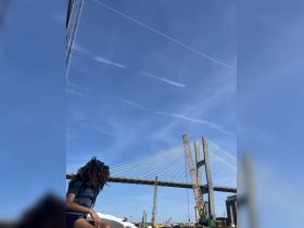 A young person enjoys the view of a stunning bridge from a boat, capturing the essence of a memorable day on the water.