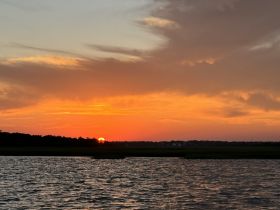 A stunning sunset over calm waters, creating a picturesque backdrop for evening boat outings.