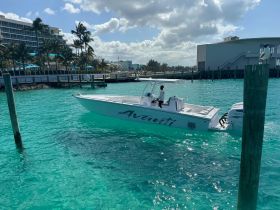 A sleek boat named 'Avanti' navigates through crystal-clear turquoise waters, showcasing a vibrant coastal backdrop — perfect for a day of adventure on the water.