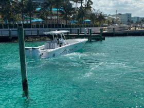 A sleek speedboat named 'Avanti' glides through crystal-clear waters, showcasing its design and elegance as it navigates near the dock.