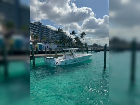 A sleek speedboat named 'Avanti' docked in crystal-clear waters, surrounded by a picturesque backdrop of palm trees and buildings, perfect for a day on the water.