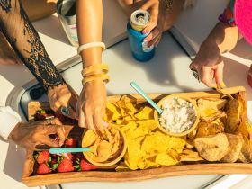 A vibrant spread of snacks, including chips, dips, and strawberries, enjoyed by guests on a boat — perfect for a fun day on the water.
