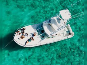 A lively group relaxes on the deck of a boat, enjoying the clear turquoise waters — perfect for a fun day out on the water.