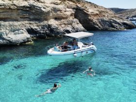 A group enjoys a sunny day on the water, with one person swimming and others relaxing on the boat, showcasing the perfect summer getaway.