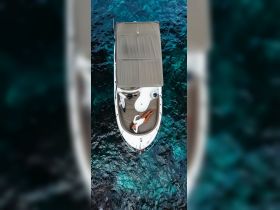 An aerial view of a woman relaxing on a boat, enjoying the serene turquoise waters — a perfect scene for sunbathing and relaxation on the water.