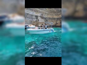 A group of friends enjoys a day on the water aboard a charter boat, surrounded by stunning turquoise waters and rocky cliffs — perfect for exploring coastal destinations.