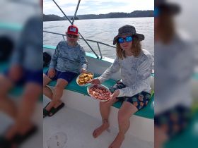 Two guests enjoy a selection of snacks aboard a boat, showcasing the perfect onboard amenities for a relaxing day on the water.