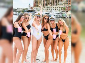 A lively group of friends celebrates at the beach, enjoying drinks and fun in the sun — perfect for bachelorette parties or summer getaways.