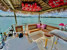 A cozy interior view of a boat's lounge area featuring comfortable seating and a helm, perfect for relaxing while enjoying the scenic waterfront.